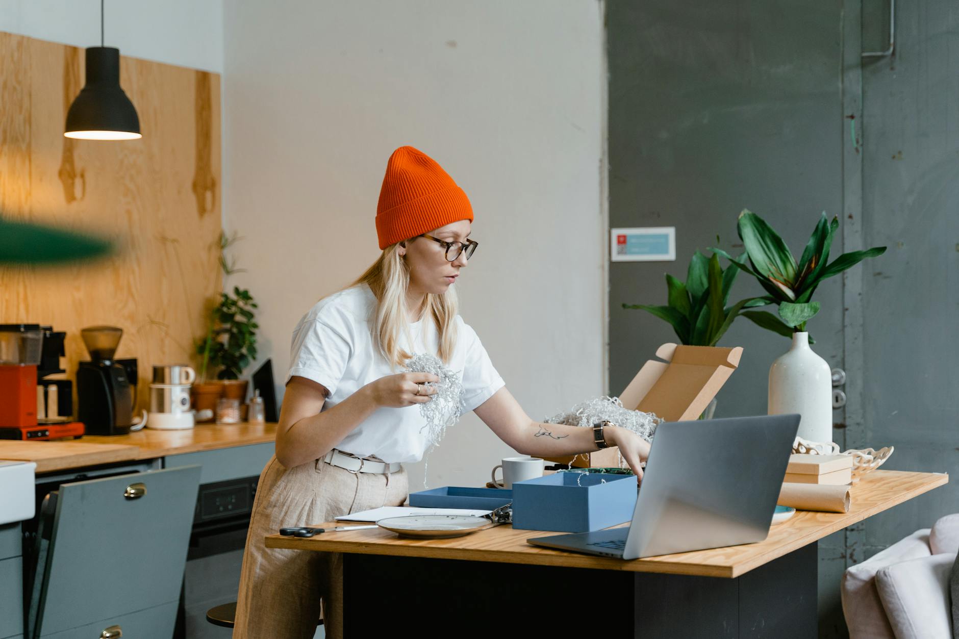 a woman in red beanie working on her laptop on the table